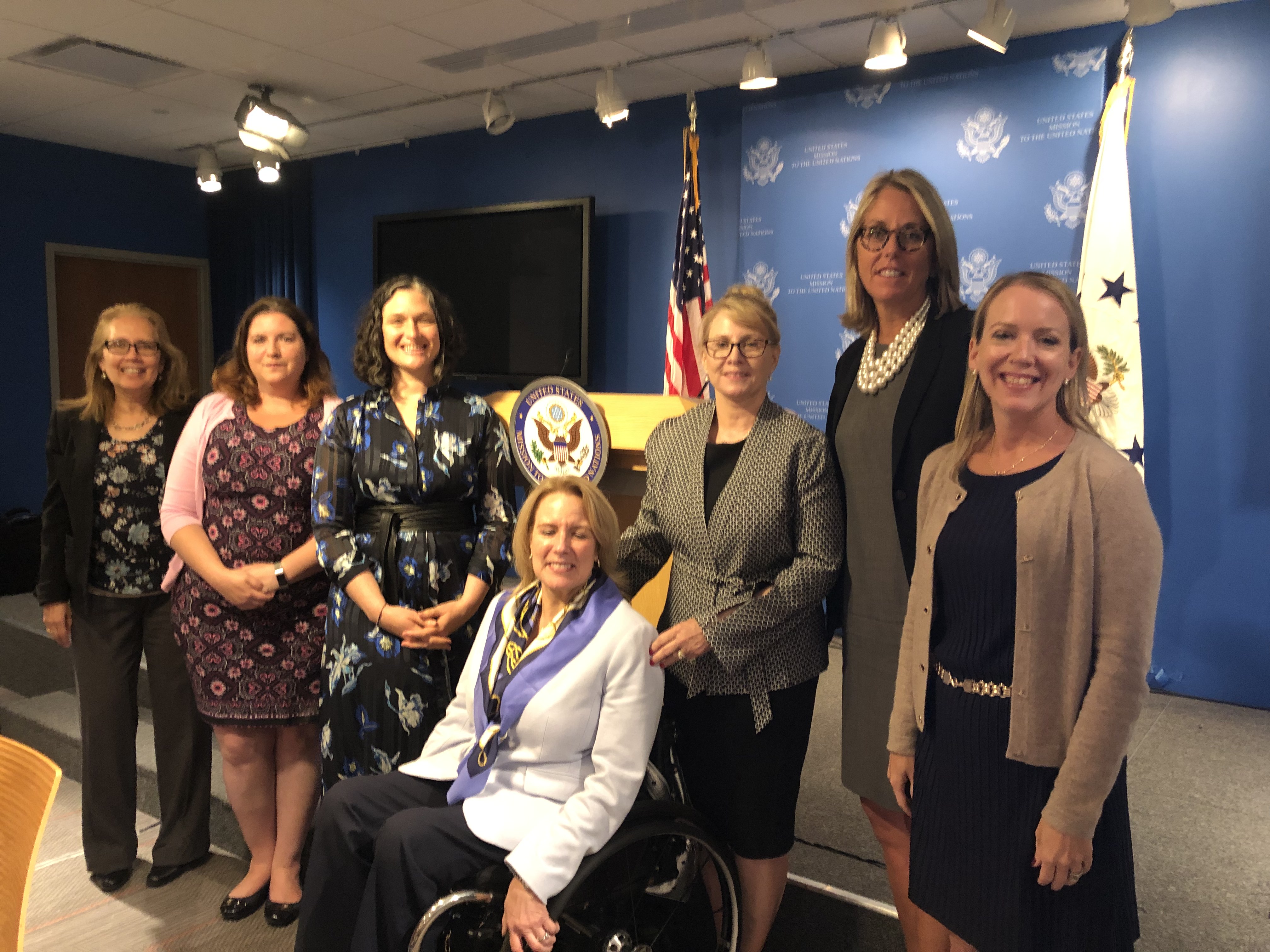 Group of women accessible leaders with apparent and non-apparent disabilities wearing business professional attire and standing in front of a podium