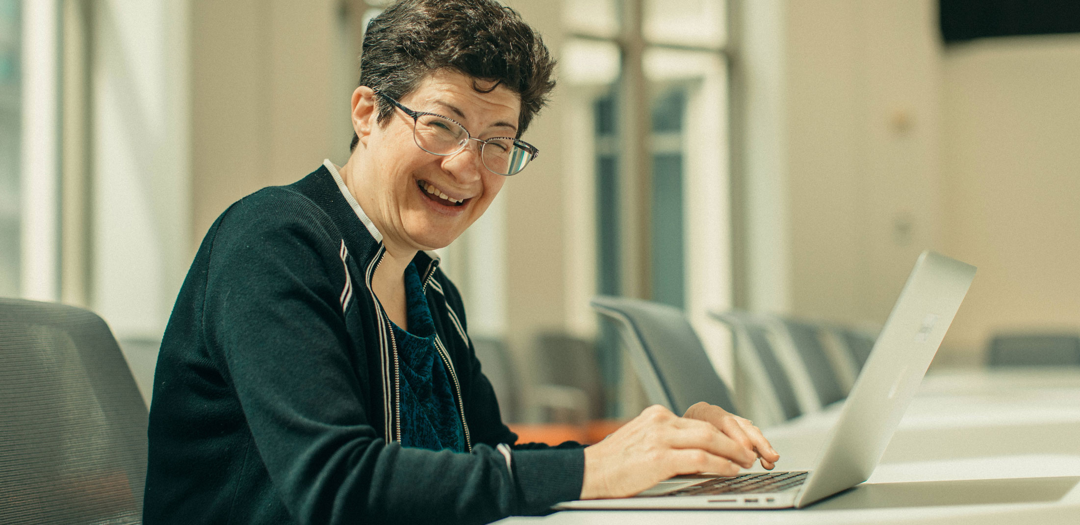 Woman smiling and using a laptop.