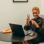 A businesswoman communicating in ASL on a zoom meeting sitting in her office