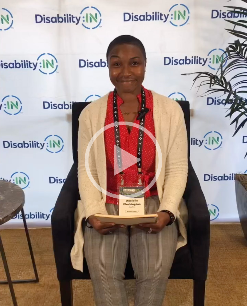 Danielle Washington, a Black woman, sitting in a chair in front of a Disability:IN background.