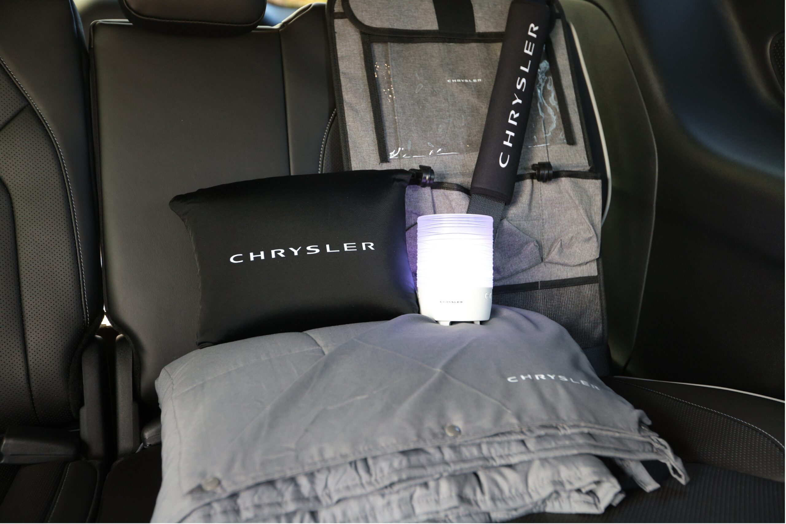 Elements of the Chrysler Calm Cabin package, including a weighted blanket, pillow, sound machine, seat back organizer, and seat belt sleeve. 