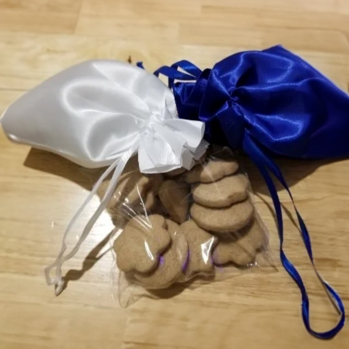 White, blue, and clear bags of teacakes on a wooden table.