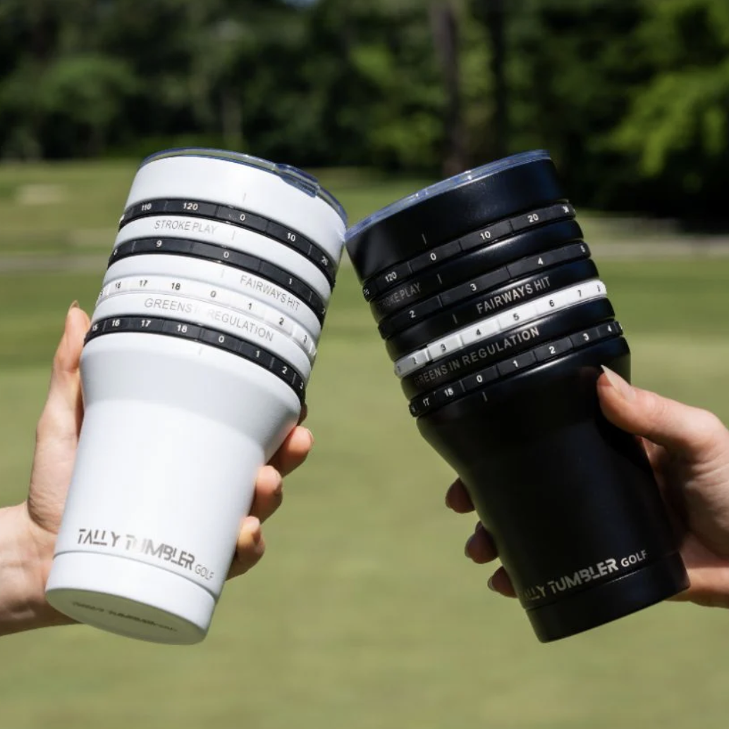 Two hands clinking two Tally Tumbler Golf Tumblers in white and black.